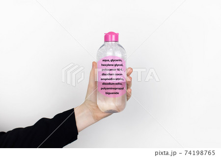 A woman is holding an micellar water. Harmful composition of ingredients. The concept of hazardous substances in cosmetics and household chemicals A woman is holding an micellar water. Harmful composition of ingredients. The concept of hazardous substances in cosmetics and household chemicals 74198765