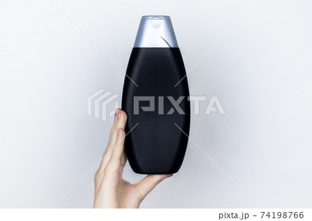 Chemical components of the shampoo. A woman's hand holds a black jar of shampoo. Place for text. Conception of the harm of chemical cosmetics or the benefits of organic chemicals for home 74198766