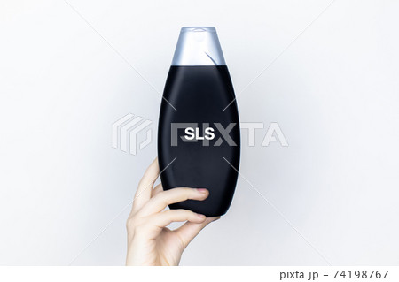 Chemical components on the shampoo label: Sodium Lauryl Sulfate (sls, sles). A hand holds a jar and a magnifier, where the harmful ingredients of a detergent are written in close up. Chemical components on the shampoo label: Sodium Lauryl Sulfate (sls, sles). A hand holds a jar and a magnifier, where the harmful ingredients of a detergent are written in close up. 74198767