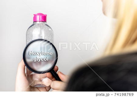 A woman examines the harmful ingredients of the micellar waterthrough a magnifying glass. Means with hexylene glycol. The concept of hazardous substances in cosmetics and household chemicals A woman examines the harmful ingredients of the micellar waterthrough a magnifying glass. Means with hexylene glycol. The concept of hazardous substances in cosmetics and household chemicals 74198769