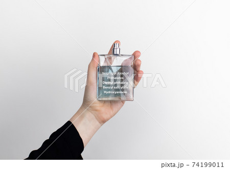 The woman is holding a perfume. Hazardous substances are indicated on the eau de toilette label. The concept of harmful components in cosmetics and household chemicals 74199011