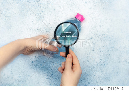 A bottle of micellar water floating in soapy water. Harmful composition of ingredients. Cleanser with Disodium Cocoamphodiacetate. The concept of hazardous substances in cosmetics and household 74199194