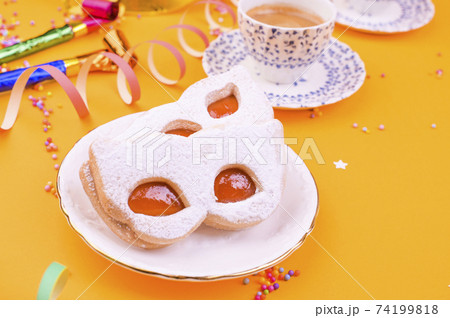 Cookies with powdered sugar in the form of a carnival mask and espresso on a yellow background 74199818