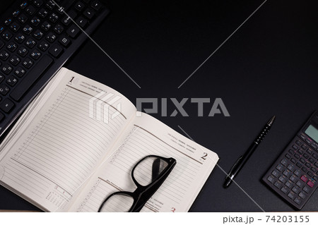 Black desk office with keyboard, calculator and other work supplies. Top view with copy space for input the text. Designer workspace on desk table essential elements on flat lay. Place for an Black desk office with keyboard, calculator and other work supplies. Top view with copy space for input the text. Designer workspace on desk table essential elements on flat lay. Place for an 74203155