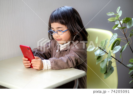 スマホを見ながら勉強する女の子 74205091