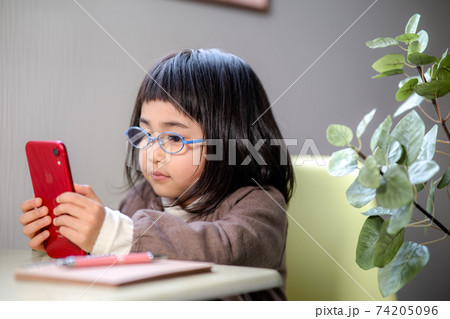 スマホを見ながら勉強する女の子 74205096