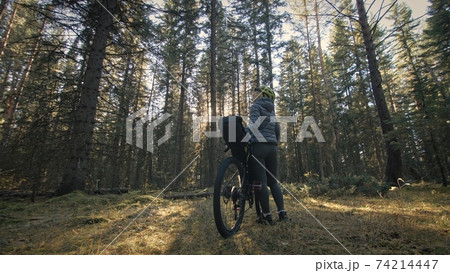 The woman travel on mixed terrain cycle touring with bike bikepacking. The traveler journey with bicycle bags. Magic forest park. The woman travel on mixed terrain cycle touring with bike bikepacking. The traveler journey with bicycle bags. Magic forest park. 74214447