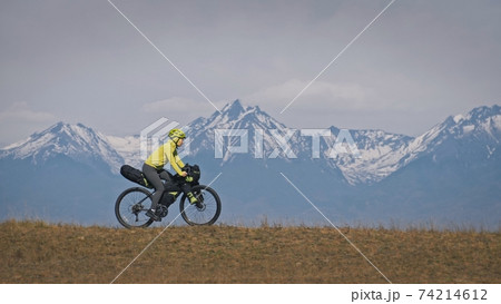 The woman travel on mixed terrain cycle touring with bikepacking. The traveler journey with bicycle bags. Sport tourism bikepacking. 74214612