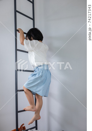 かわいい女の子が家の手すりに登って遊んでいる姿　girl home　 74217343