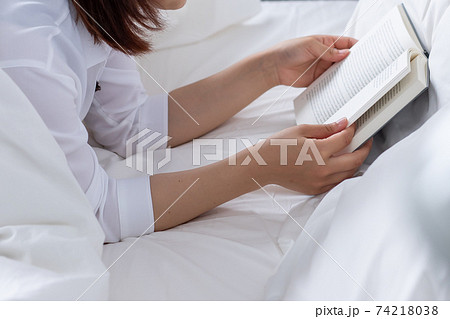 代の女の子がベットで読書をしている写真の写真素材