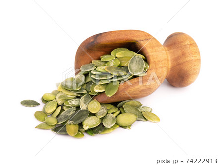 Pumpkin seeds in wooden scoop, isolated on white background. Green pepita seeds. Pumpkin seeds in wooden scoop, isolated on white background. Green pepita seeds. 74222913