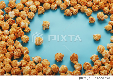 Caramel popcorn by a ripple on a blue background, in the form of a frame. 74228758