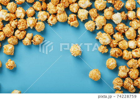Caramel popcorn by a ripple on a blue background, in the form of a frame. 74228759