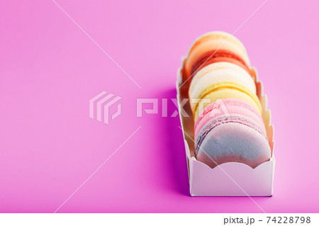 Colorful French macarons cookies in a package on a pink background. Colorful French macarons cookies in a package on a pink background. 74228798