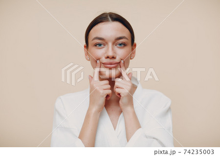 Young woman doing face building facial gymnastics self massage and rejuvenating exercises 74235003