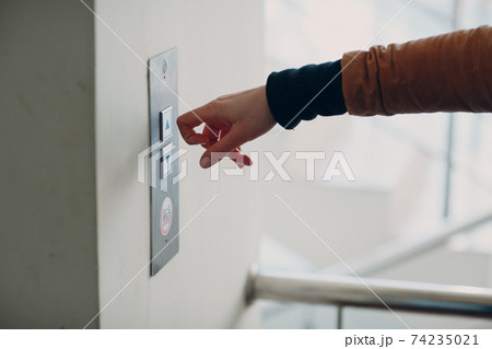 Close up of forefinger knuckle pressing the button elevator during coronavirus pandemic covid-19 quarantine concept 74235021