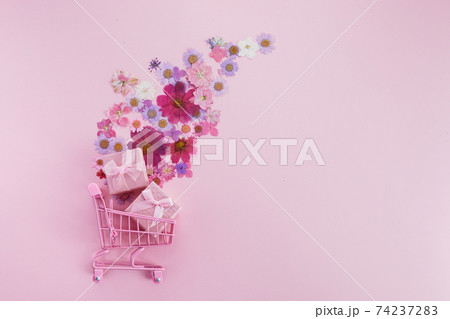 Flowers fly out of the pink shopping cart on a pink background. Season sale, spring shoping concept. Valentines day. 74237283