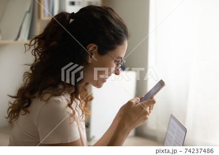 Happy smiling young lady holding mobile phone reading good news 74237486
