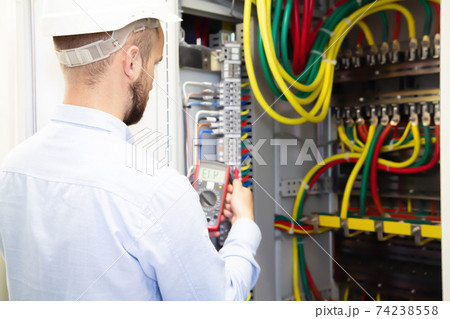 Electrician engineer measures voltage in power electrical cabinet Electrician engineer measures voltage in power electrical cabinet 74238558