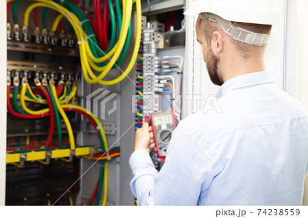 Electrician engineer measures voltage in power electrical cabinet Electrician engineer measures voltage in power electrical cabinet 74238559