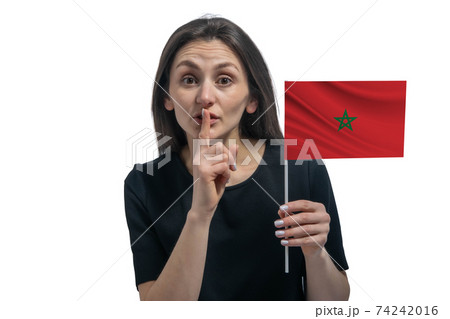 Happy young white woman holding flag of Morocco and holds a finger to her lips isolated on a white background Happy young white woman holding flag of Morocco and holds a finger to her lips isolated on a white background 74242016