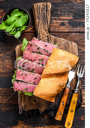 Grilled Ahi Tuna Steak and Avocado Sandwich with arugula on a cutting board. Dark wooden background. Top view 74245817