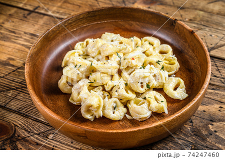 Ravioli or tortellini pasta in cream cheese sauce with meat. wooden background. Top view Ravioli or tortellini pasta in cream cheese sauce with meat. wooden background. Top view 74247460