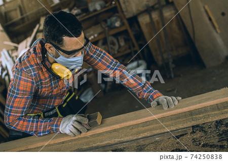 carpenter is working in a woodworking office.caucasion white Carpenter using sandpaper to polish the wood and brush off the sawdust. carpenter is working in a woodworking office.caucasion white Carpenter using sandpaper to polish the wood and brush off the sawdust. 74250838