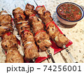 shish kebab on skewers on a plate and salsa sauce. 74256001