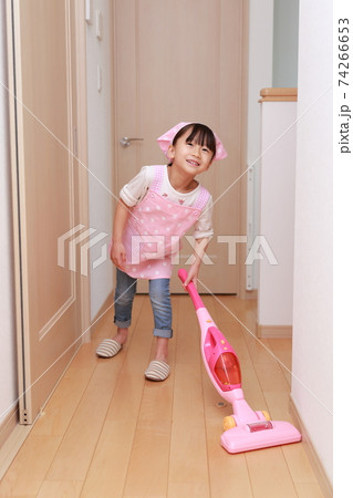掃除機のおもちゃで主婦のお飯事をする5歳の女の子の写真素材