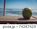 Coconut with a tube on the windowsill. Ocean view. Coconut water drink. 74267420