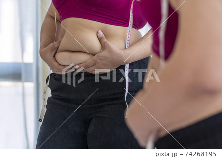 Obesity unhealthy concept. Reflection of overweight woman wear sport bar with measure tape on body Obesity unhealthy concept. Reflection of overweight woman wear sport bar with measure tape on body 74268195
