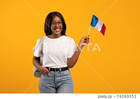 Happy black woman showing french flag on yellow 74269351