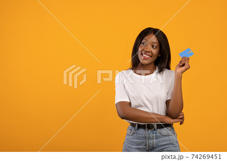 Smiling black woman with credit card looking at copy space 74269451