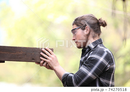 Carpenter, he is working in the workshop. Man at work on wood. Image of mature carpenter in the workshop, furniture making concept. 74270518