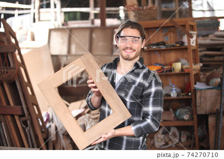 Carpenter, he is working in the workshop. Man at work on wood. Image of mature carpenter in the workshop, furniture making concept. Carpenter, he is working in the workshop. Man at work on wood. Image of mature carpenter in the workshop, furniture making concept. 74270710