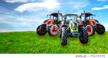 Agricultural advertisement banner - group of new and modern generic tractors on a green meadow in sunny day (mixed). 74270745