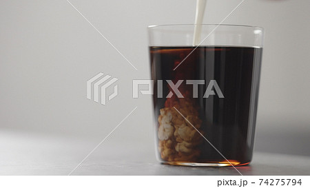 pour cream in cola in tumbler glass on concrete countertop with copy space 74275794