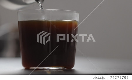pour water in coffee in tumbler glass on concrete countertop with copy space 74275795