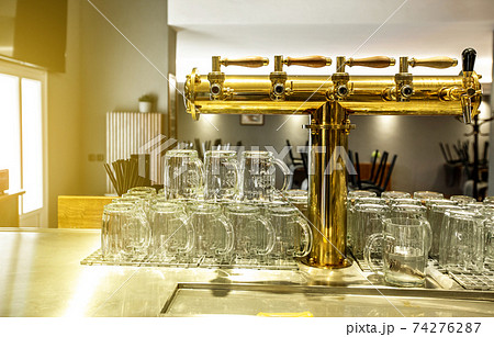Close up of a beer faucet or tap with huge arrenge of an empty glasses in the bar or pub, restaurant concept 74276287