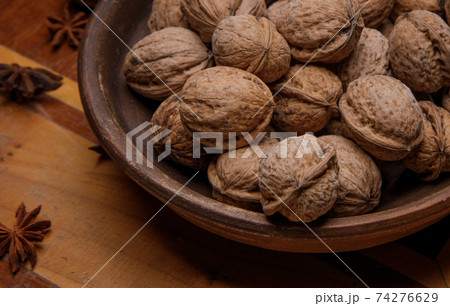 Nuts. whole walnuts in an earthenware dish on a dark wooden table. Nuts. whole walnuts in an earthenware dish on a dark wooden table. 74276629
