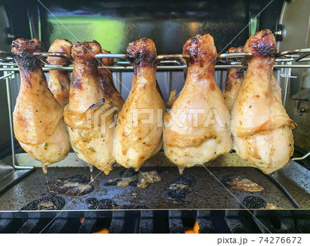 Grilled chicken drumsticks are cooked in gas grill 74276672