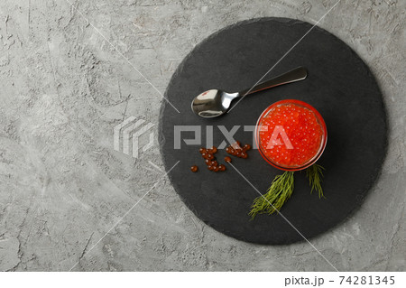 Tray with glass of red caviar, spoon and dill on gray background, space for text 74281345