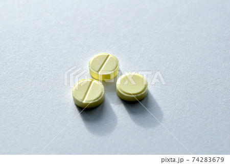 Three round pills lie on white. 74283679