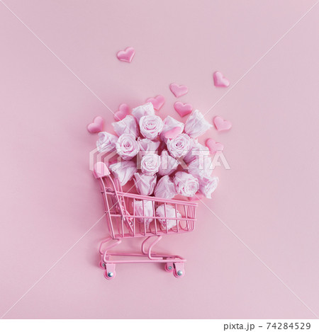 Shopping cart with pink roses and hearts on pink background. Romanitc concept Shopping cart with pink roses and hearts on pink background. Romanitc concept 74284529