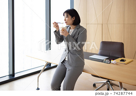 オフィスでカップ麺を食べる女性 74287744