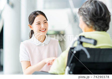 車いすの高齢者と話す介護士 74290378