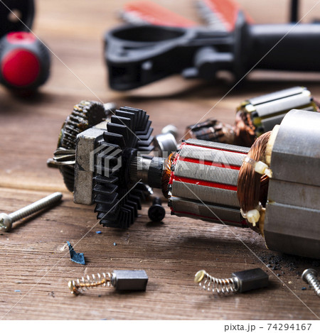 Power tool repair. Details of electrical appliance and repair tools on a wooden table in a repair shop 74294167