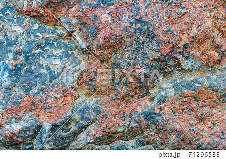 Chipped red gray granite stone close-up, beautiful texture, rough textured surface, exposure to atmosphere, outdoors. Chipped red gray granite stone close-up, beautiful texture, rough textured surface, exposure to atmosphere, outdoors. 74296533