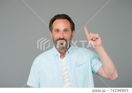 Inspired mature man with stylish beard hair smile keeping index finger raised grey background, idea Inspired mature man with stylish beard hair smile keeping index finger raised grey background, idea 74296805